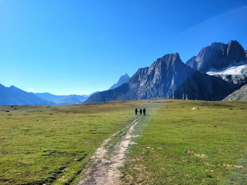 a group of people walking on a dirt path in front of a mountain