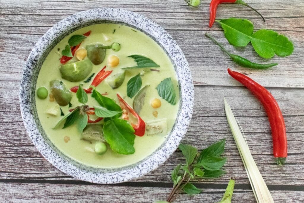 A bowl of vegan green curry served with tofu and vegetables.