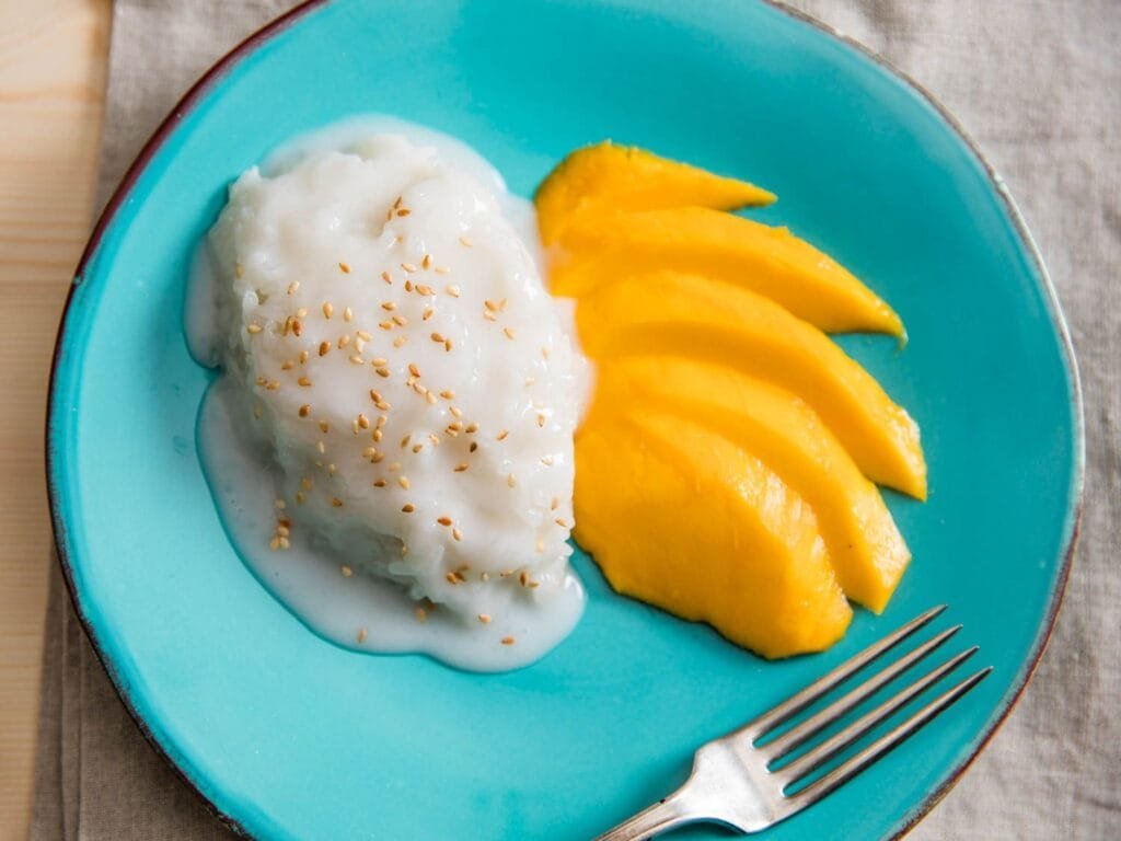 A plate of mango sticky rice with a side of coconut cream.