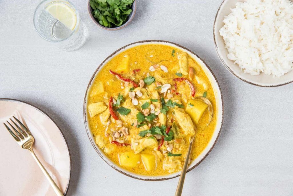 A plate of rich and creamy Massaman curry served with white rice.